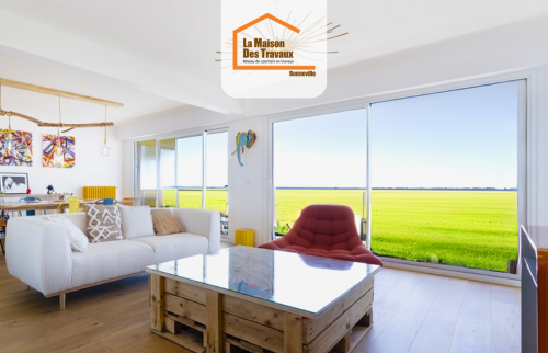 Salon contemporain avec baie vitrée donnant sur la nature, mobilier design et parquet clair – aménagement intérieur lumineux en Haute-Savoie.