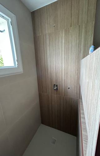 Pose du carrelage effet bois dans l'espace douche pour une ambiance naturelle et contemporaine.