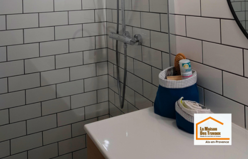 Vue d’ensemble d’une salle de bain moderne rénovée près du Tholonet avec douche à l’italienne, meuble vasque suspendu et carrelage métro blanc.