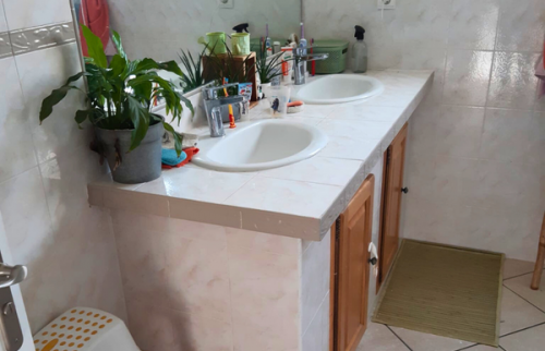 Salle de bain avant travaux avec baignoire et carrelage beige d’origine.