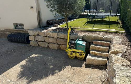 Compactage du sol et réalisation d’un escalier en pierre pour faciliter les accès entre les différents niveaux du terrain.