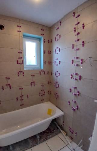 Pose du carrelage mural en cours dans la salle de bain à Courrières