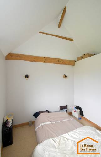 Chambre sous toiture après isolation thermique intérieure et rénovation, avec conservation des poutres apparentes à Saint-Cassien.