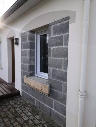 Fermeture de l'ancienne porte de garage sectionnelle par le maçon et pose de la nouvelle fenêtre PVC double vitrage