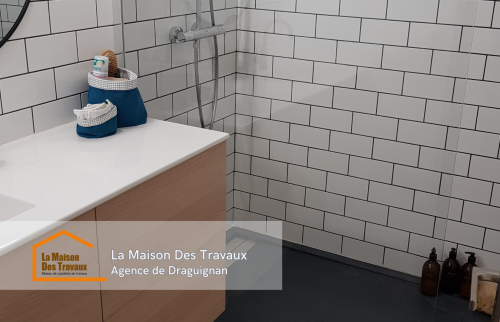 Vue de la salle de bain rénovée avec un carrelage métro élégant et une douche à l’italienne moderne.