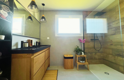 Salle de bain finalisée avec douche XXL et mobilier bois.