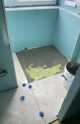 Pose du carrelage sur natte d'étanchéité prévue à cet effet 