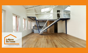 Aménagement d’un ancien dépôt en loft moderne et lumineux à Villeneuve-sur-Lot, avec parquet et mezzanine design. 