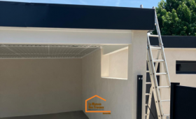 Construction d’un carport en Haute-Savoie avec structure maçonnée, toit plat moderne et finition noire – vue latérale avec échelle.