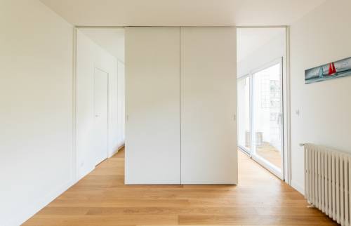 Porte cachée derrière une bibliothèque dans un salon moderne à Paris 16e.