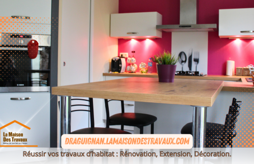 La cuisine rénovée dévoile une crédence rouge moderne, contrastant élégamment avec les meubles blancs et le plan de travail en bois clair, pour un espace à la fois pratique et chaleureux.