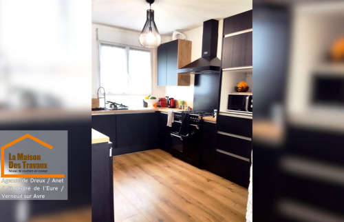 Après rénovation : Nouvelle cuisine contemporaine avec des meubles noirs et bois, un parquet stratifié chaleureux et des équipements haut de gamme.