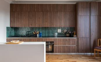 Cuisine design avec placards en bois foncé et appareils en noir à Paris 8e.