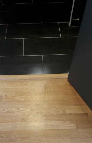 Carrelage noir dans la salle de bain et parquet dans la chambre