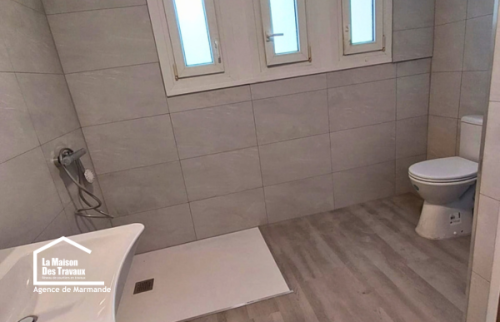 Aménagement d’une salle d’eau accessible à Castillonnès avec douche sans ressaut, robinetterie murale et lavabo suspendu.