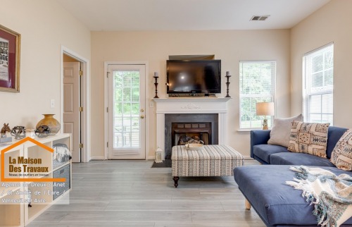 Rénovation salon moderne près de Dreux – Transformation élégante avec sol effet bois, cheminée blanche et canapé bleu cosy. Un intérieur lumineux et chaleureux.
