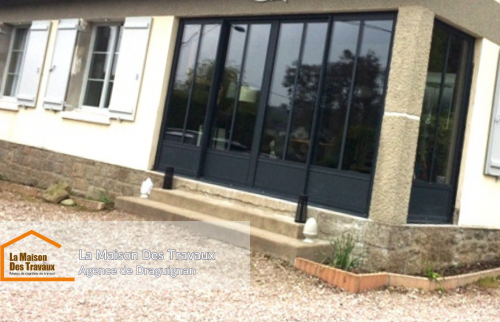 Façade rénovée avec une avancée fermée, intégrant des baies vitrées modernes en aluminium noir.