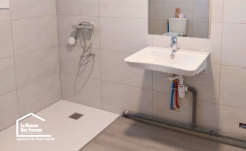 Salle de bain PMR rénovée à Castillonnès avec douche de plain-pied, lavabo suspendu et espace dégagé pour faciliter les déplacements.