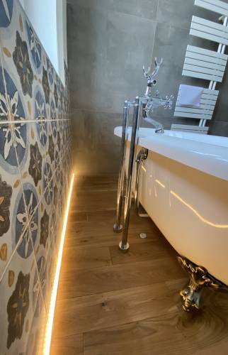 Eclairage élégant au sol de la salle de bain avec baignoire en pattes de lions