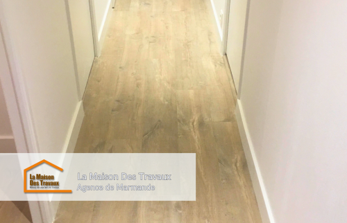 Gros plan sur le parquet du couloir, mettant en avant la texture et les nuances boisées du sol. 