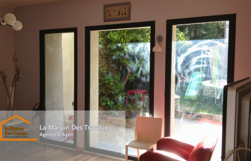 L’intérieur après transformation :** Un séjour lumineux et accueillant grâce aux nouvelles ouvertures, offrant une vue directe sur le jardin.