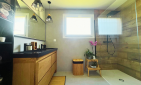 Salle de bain finalisée avec douche XXL et mobilier bois.
