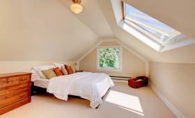 Chambre aménagée sous les combles avec lumière naturelle et toiture mansardée
