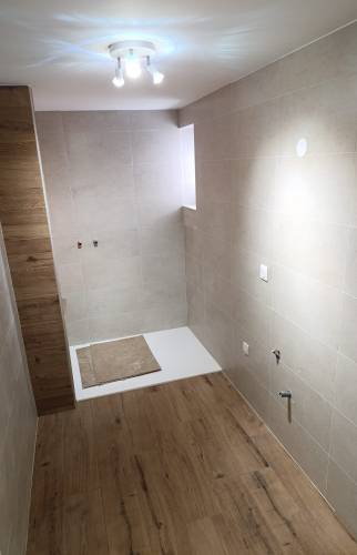 Pose du carrelage effet bois et du revêtement mural lors de la rénovation d’une salle de bain accessible à Charancieu.