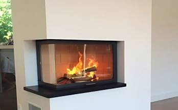Cheminée moderne avec foyer vitré d’angle et feu de bois en fonctionnement – rénovation intérieure à Bonneville en Haute-Savoie.