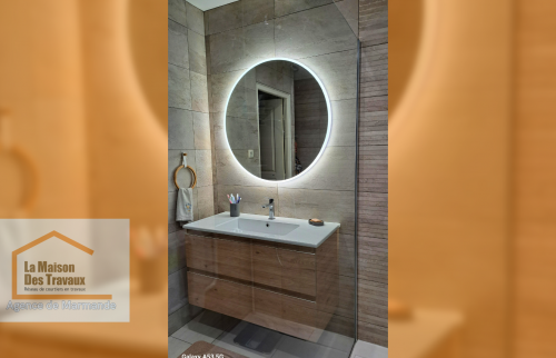 	Salle de bain moderne avec miroir LED rond : Offrez-vous une salle de bain élégante et pratique avec un miroir lumineux et un meuble suspendu en bois clair.