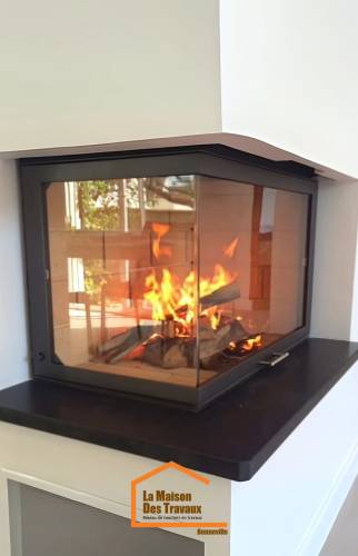 Gros plan sur un foyer vitré d’angle avec flammes actives et habillage noir – installation de cheminée à Bonneville en Haute-Savoie.
