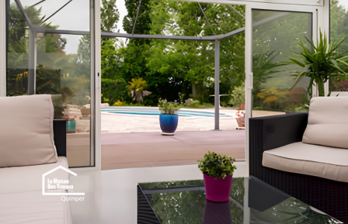 Aménagement intérieur d’une véranda à Plomelin avec salon confortable et grandes surfaces vitrées pour créer une véritable pièce de vie supplémentaire.