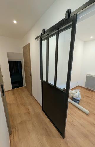 Installation d’une verrière coulissante noire pour structurer les espaces lors d’une rénovation intérieure à Voiron.