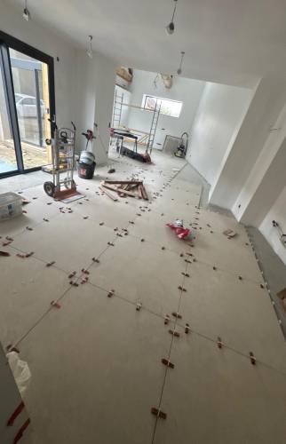 Pose du carrelage grand format dans la pièce de vie lors des finitions du chantier de rénovation.