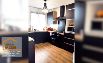 Après rénovation : Nouvelle cuisine contemporaine avec des meubles noirs et bois, un parquet stratifié chaleureux et des équipements haut de gamme.