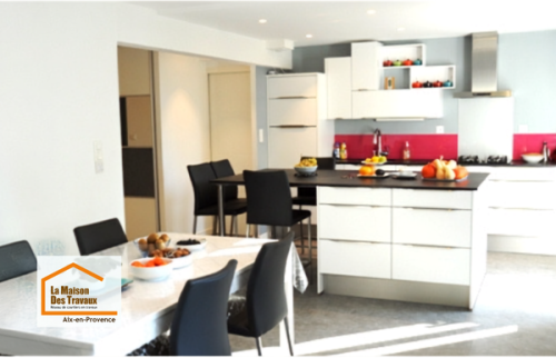 Cuisine ouverte moderne rénovée près d'Aix-en-Provence avec îlot central, grandes baies vitrées et espace repas convivial, pensée pour améliorer le confort et la circulation au quotidien.