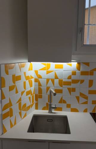 Coin évier d'une cuisine rénovée, crédence graphique orange et blanc, Paris