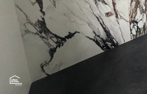 Pose de faïence grand format effet marbre pour une salle de bain moderne rénovée à Quimper par des artisans locaux.