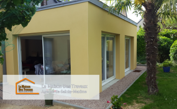 Vue intérieure de l'extension avec de grandes baies vitrées, baignant l’espace de lumière naturelle et offrant une vue apaisante sur le jardin.