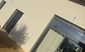 Façade rénovée avec enduit clair et menuiseries anthracite à Voiron