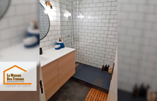 un aperçu d’une salle de bain stylisée avec un sol en hexagone noir, un lavabo en bois clair, et une douche ouverte