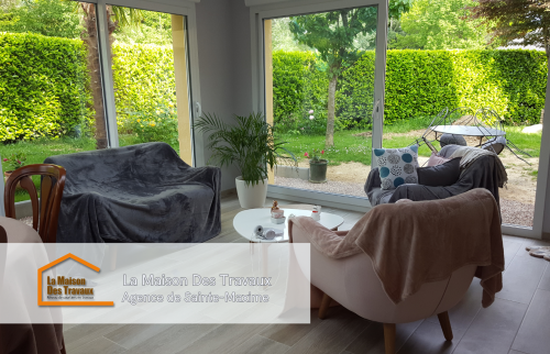 Espace salon de l’extension, aménagé confortablement, permettant de profiter d’une ambiance cosy tout en restant ouvert sur la nature environnante.