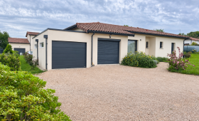 Garage en modules béton avec toit plat et porte anthracite, attenant à une maison à L’Isle-Jourdain. 