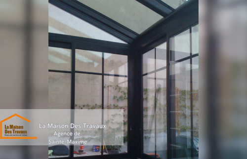 Vue de l’intérieur, où la véranda offre une luminosité accrue, avec une grande attention portée aux détails de l'installation des vitrages.  