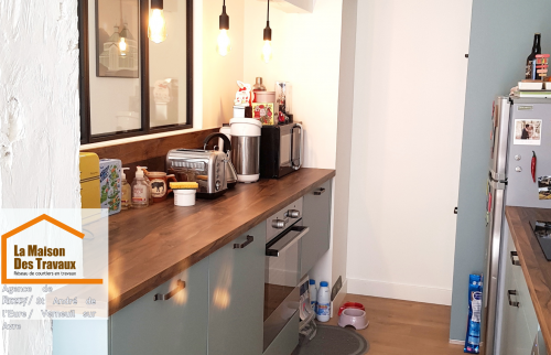 Aménagement cuisine Chérisy – Cuisine équipée avec plan de travail bois, verrière atelier et électroménager intégré, offrant un design harmonieux et pratique.