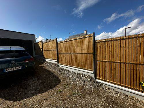 Mise en place d’une clôture rigide en bois sur muret existant, permettant de sécuriser le terrain tout en préservant l’esthétique extérieure.
