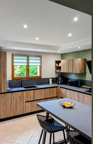 Vue d'ensemble de la cuisine, avec une belle harmonie bois, vert sauge et noir