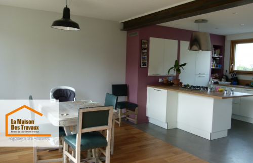 Pièce de vie moderne près de Luxeuil – Séjour ouvert avec cuisine intégrée et poutre apparente, combinant charme et modernité pour un intérieur accueillant.