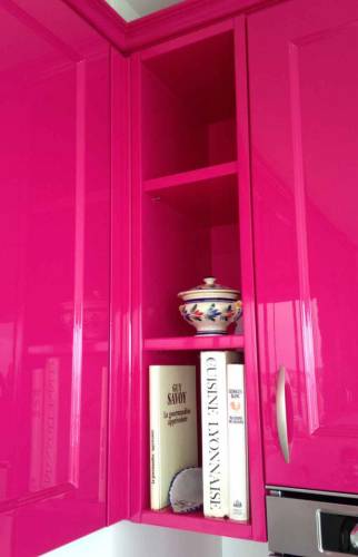 Cuisine aménagée sur-mesure avec façades laquées rose fuchsia et plan de travail en angle optimisé.