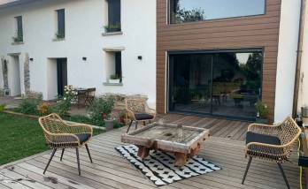 Aménagement extérieur finalisé avec terrasse bois sur-mesure devant une maison en pisé à La Côte-Saint-André : un véritable espace de vie convivial et chaleureux